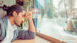 man thinking with his hand on his head on a window